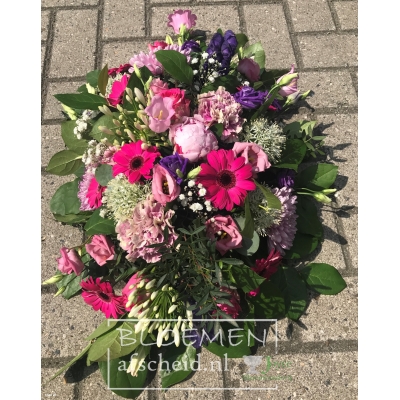 Roze rouwarrangement  in ovale vorm roze rozen en paars-blauwe bloemen